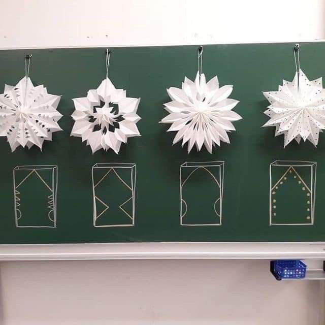 paper snowflakes are hanging on a green board