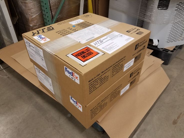 two boxes stacked on top of each other in a warehouse with tags attached to them