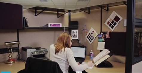 a woman sitting at a desk with a book in her hand