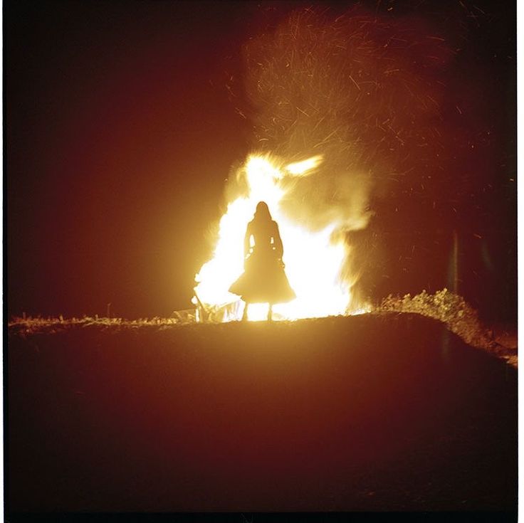 a woman standing in front of a fire