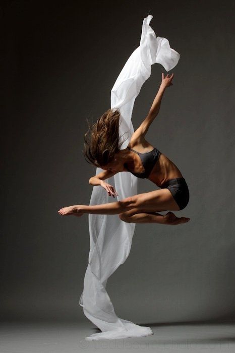 a woman is dancing with white fabric on her body