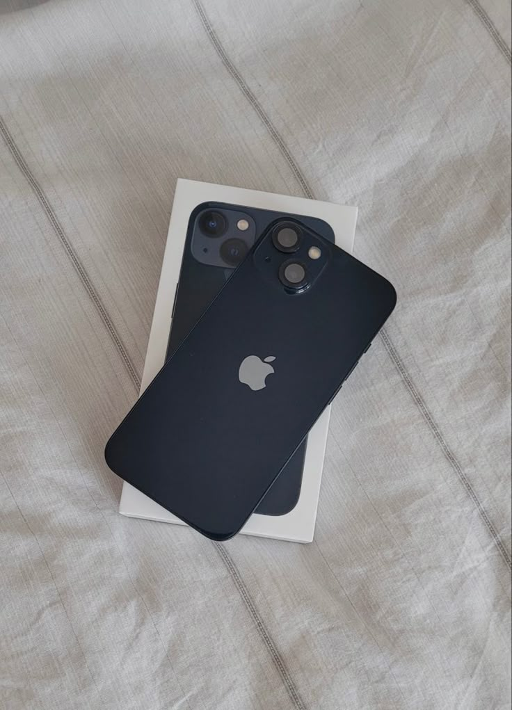 two iphones sitting on top of a bed next to each other in a box