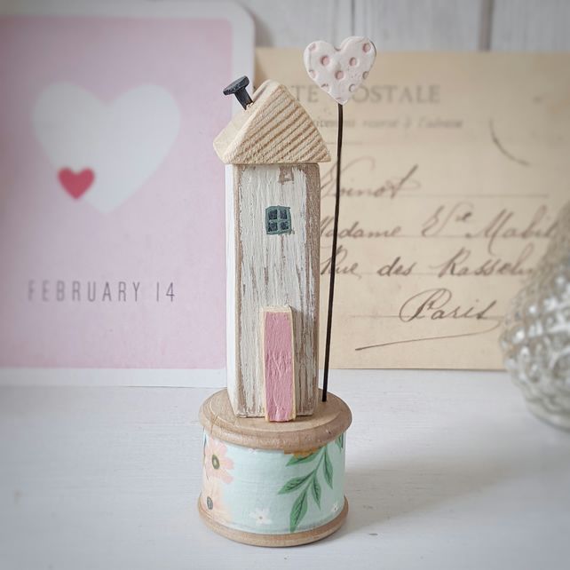 a small wooden birdhouse on top of a stand next to a postcard holder