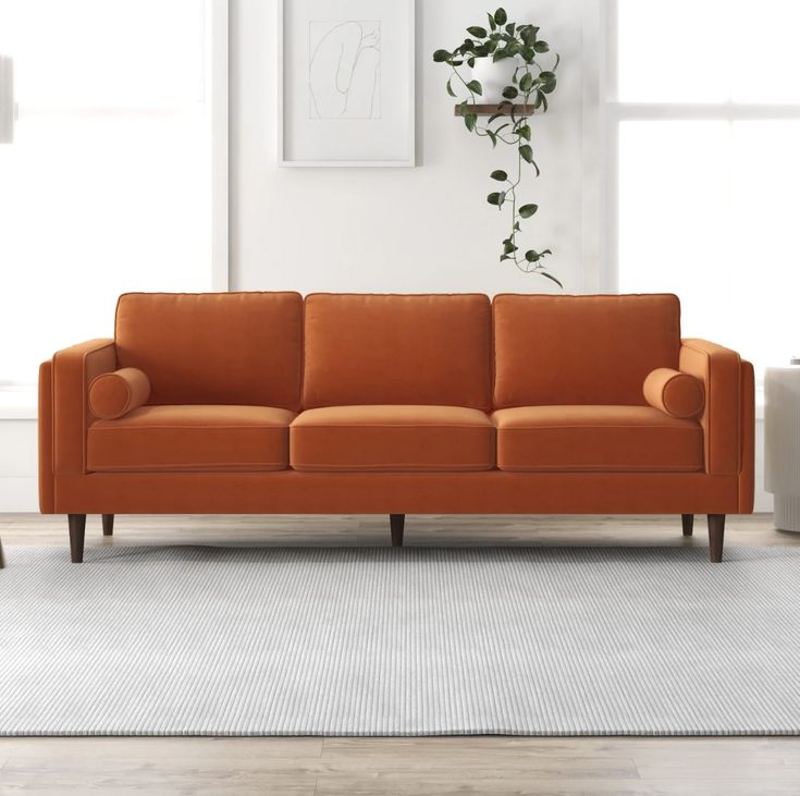 an orange couch sitting on top of a white rug