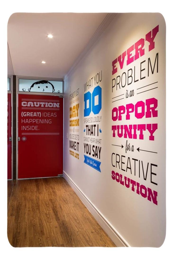 an office hallway with posters on the wall and wood flooring in front of it