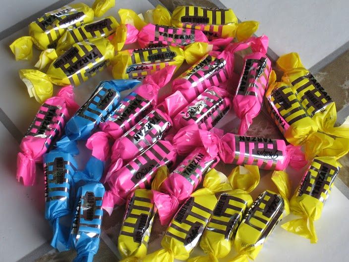 colorful candy wrapped in cellophane on top of a tile floor next to a pile of yellow and pink candies