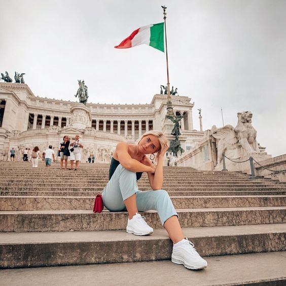 a woman sitting on the steps in front of a building with a flag flying above her head