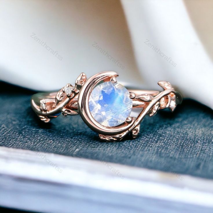 a ring with a rainbow colored stone in the center on top of a blue cloth