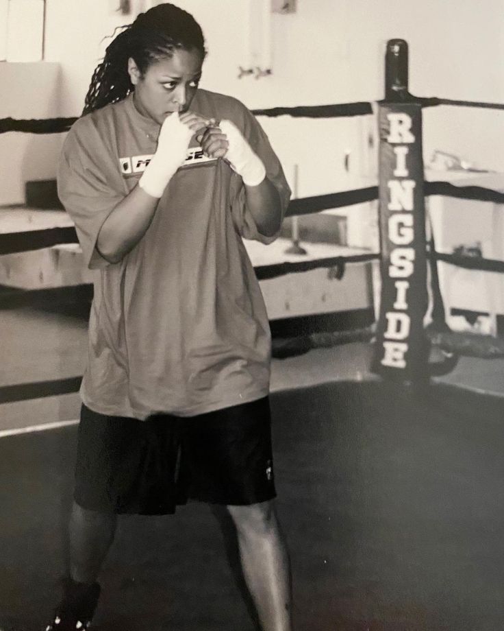 a woman standing next to a boxing ring