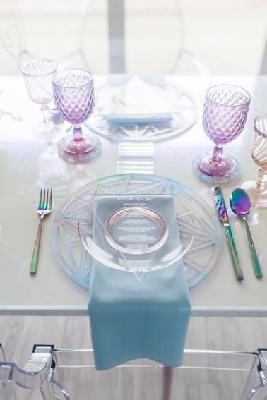 the table is set with glass dishes and silverware