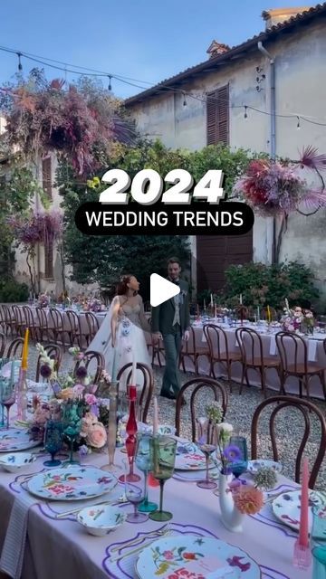 a couple standing next to each other in front of a table covered with plates and flowers