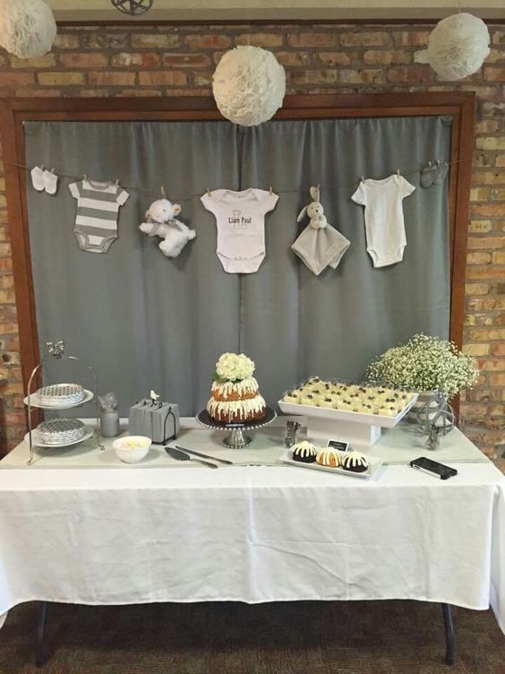 a table topped with cupcakes and cakes covered in frosting next to a brick wall