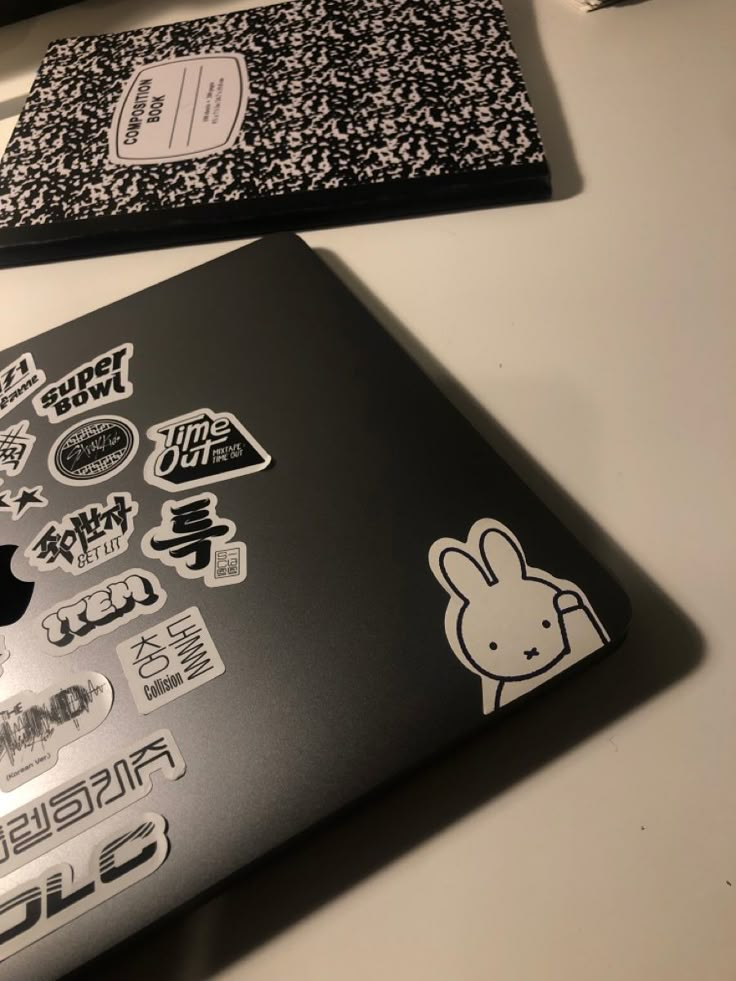 two laptops with stickers on them sitting next to each other