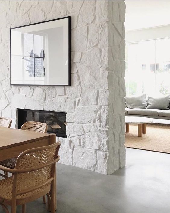 a dining room table and chairs in front of a white brick wall with a fireplace