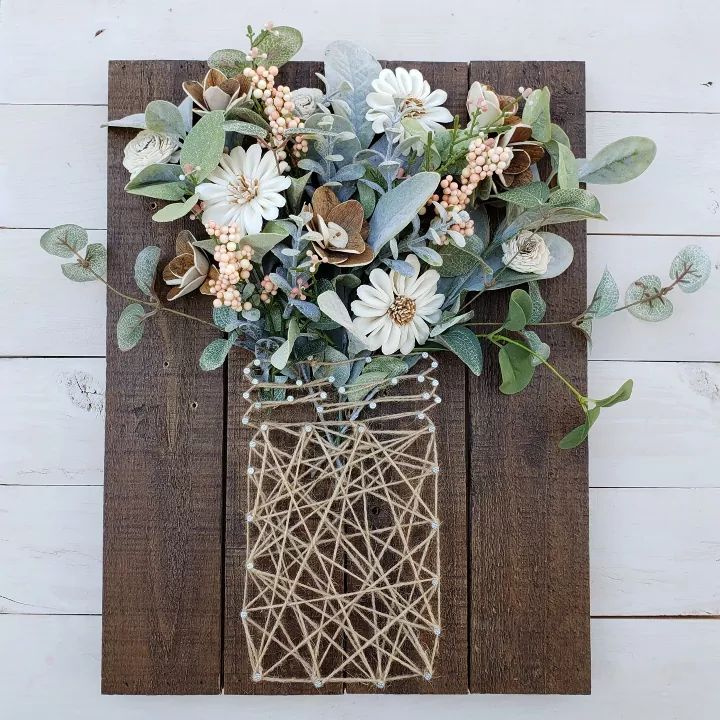 a vase filled with flowers sitting on top of a wooden wall