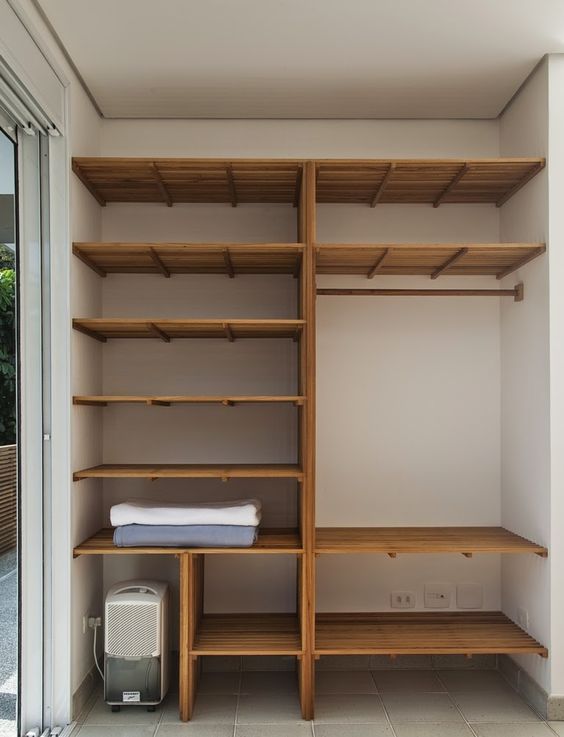 an empty walk in closet with wooden shelves and white towels on the bottom shelfs