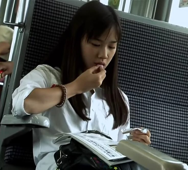 a woman sitting on a train reading a book