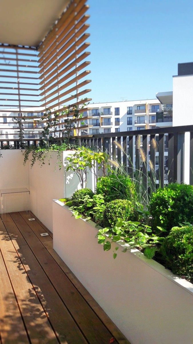 a balcony with plants and wooden flooring on top of it, next to a building