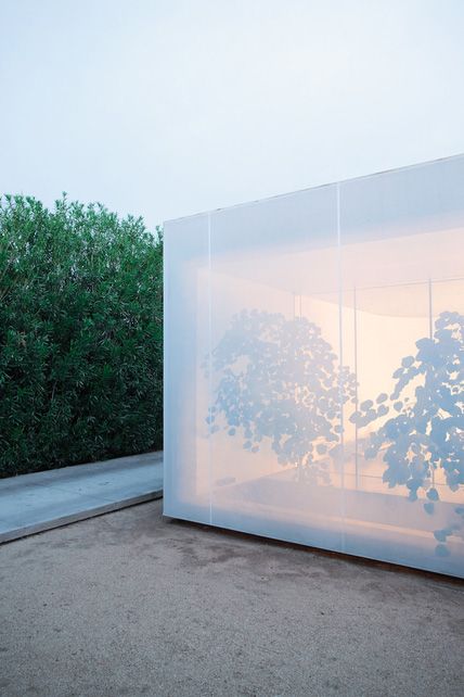 a large white box sitting on the side of a road next to a tree and bushes