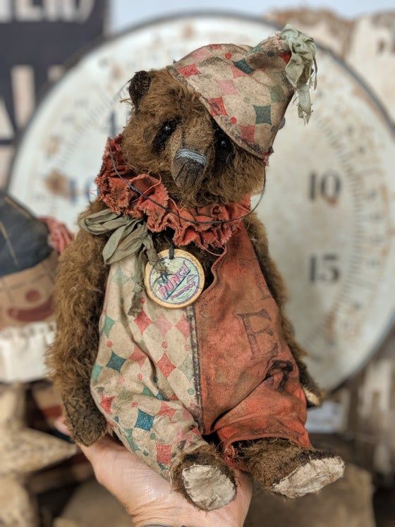 an old teddy bear wearing a hat and dress