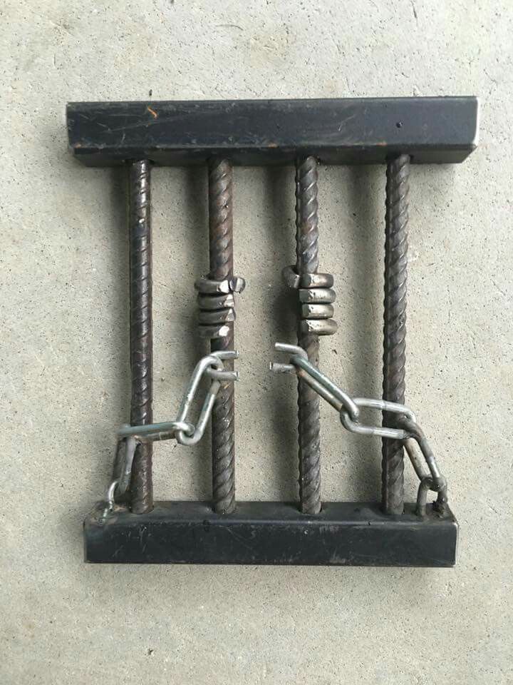 two metal bars are connected to each other on the concrete floor with chains hanging from them