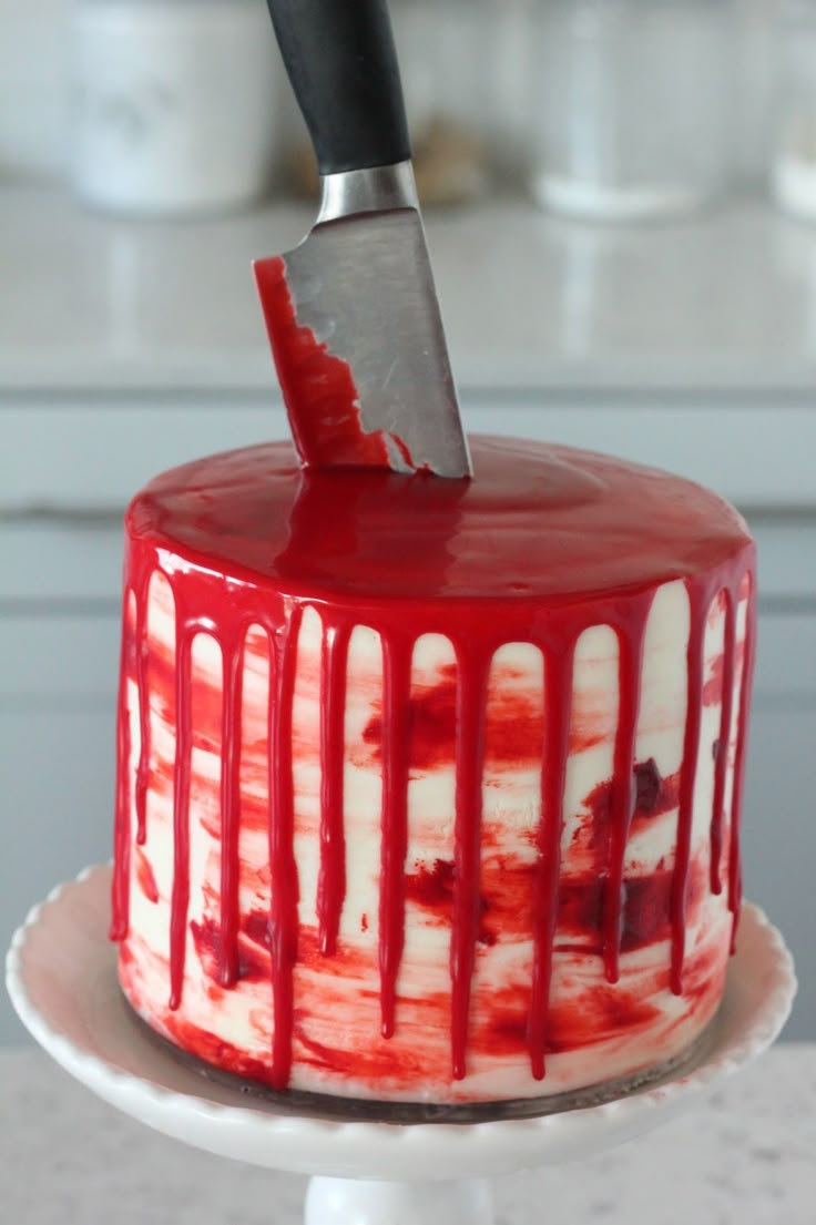 a knife stuck in the top of a red and white cake with icing on it