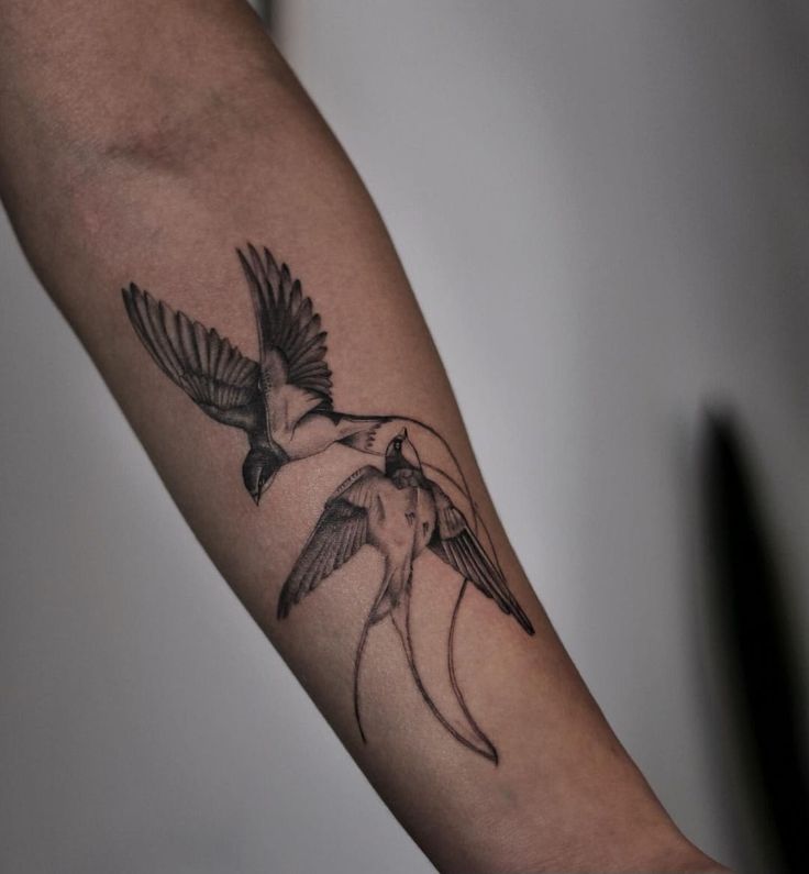 a black and white bird tattoo on the arm