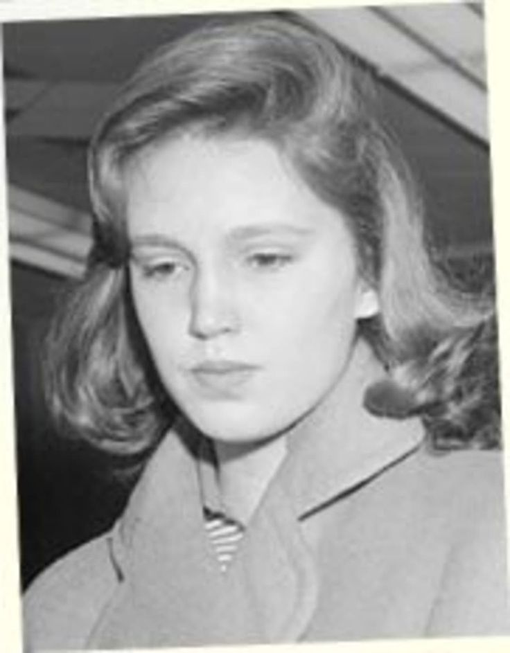 an old black and white photo of a woman wearing a suit with a striped tie