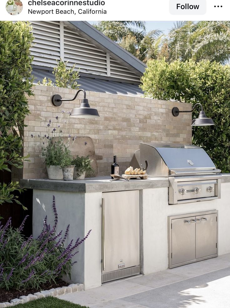 an outdoor kitchen with grill, sink and potted plants