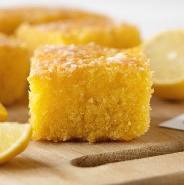 a wooden cutting board topped with slices of lemon cake