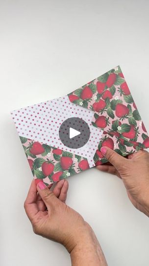 two hands holding up an envelope with apples on it and one hand is opening the envelope