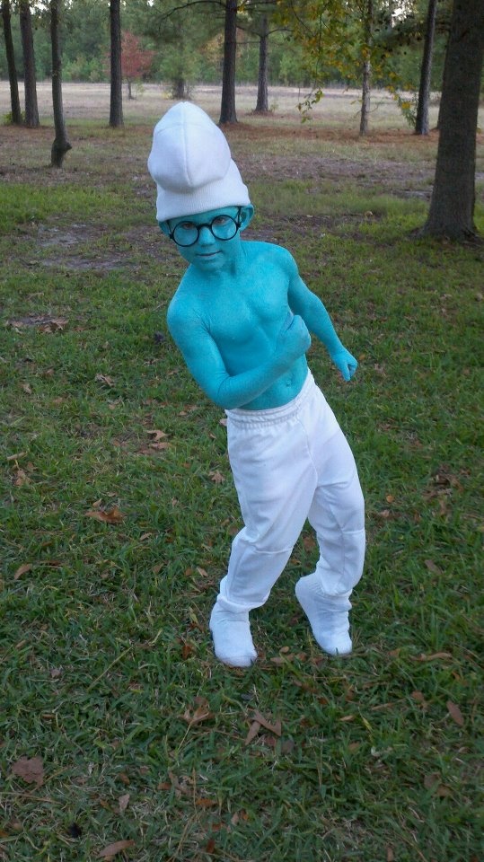 a man in blue shirt and white pants standing on grass