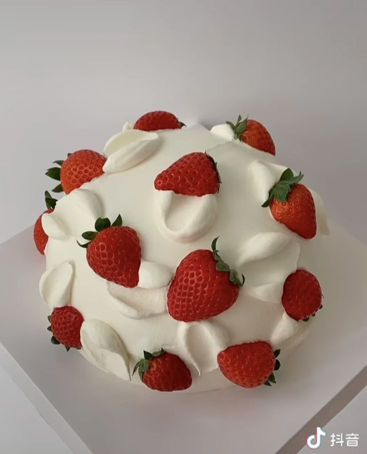 a white cake with strawberries on top and whipped cream around the edges is shown