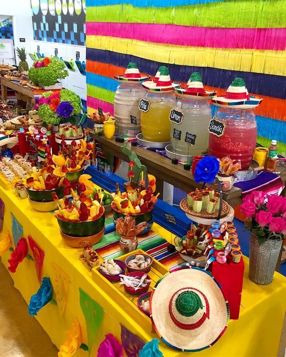 a table topped with lots of different foods and desserts on top of colorful tables