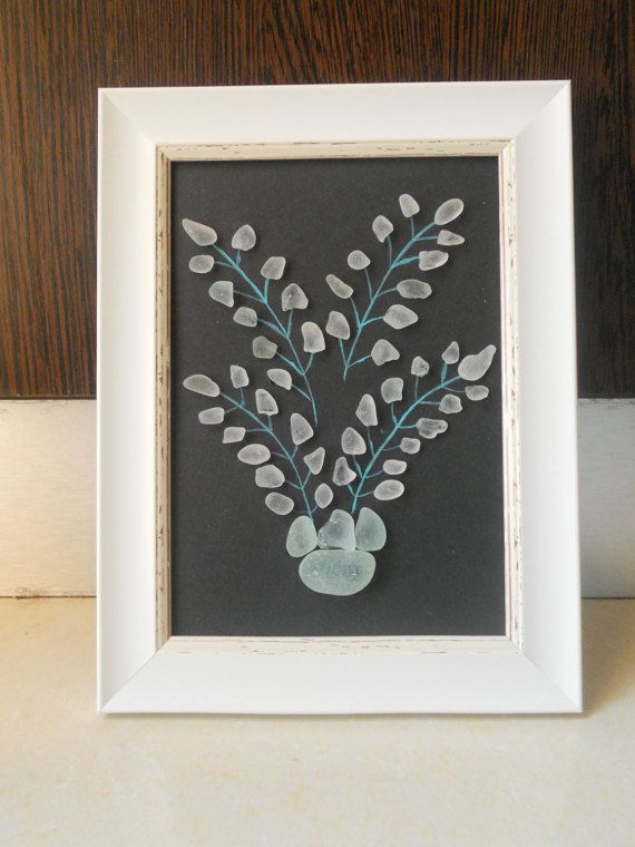 a white frame holding a paper cut out of leaves and berries on a black background