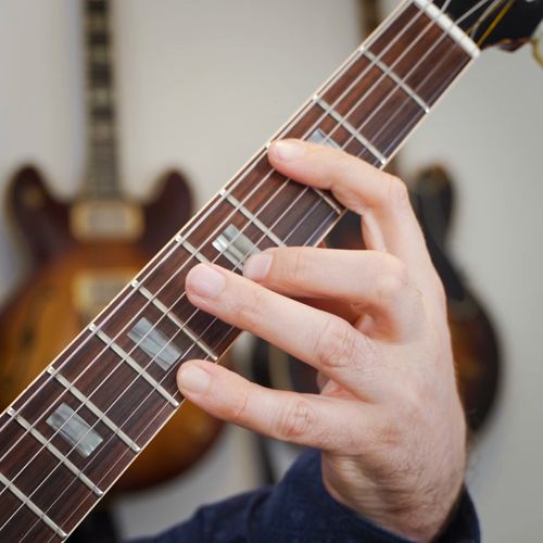 a man is holding an electric guitar in his hands and looking at the strings on it