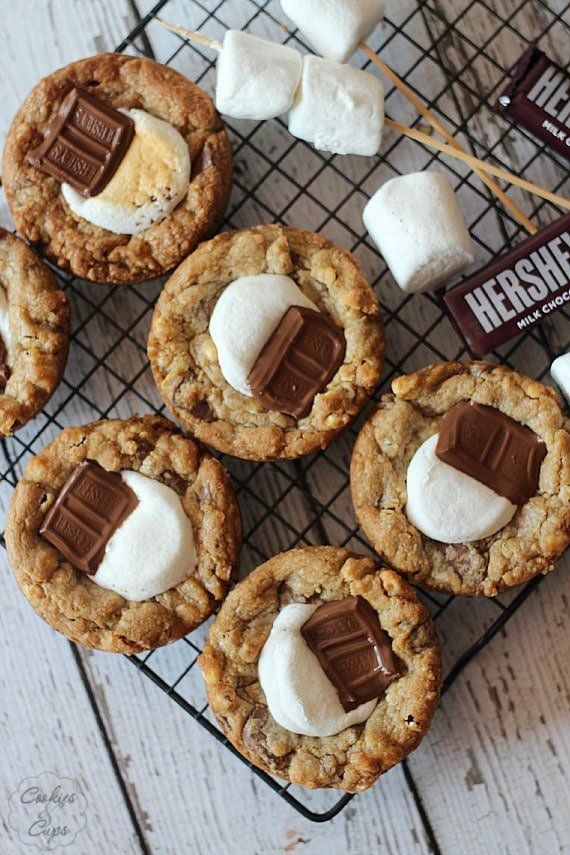 chocolate chip cookies with marshmallows on a cooling rack next to hershey bars