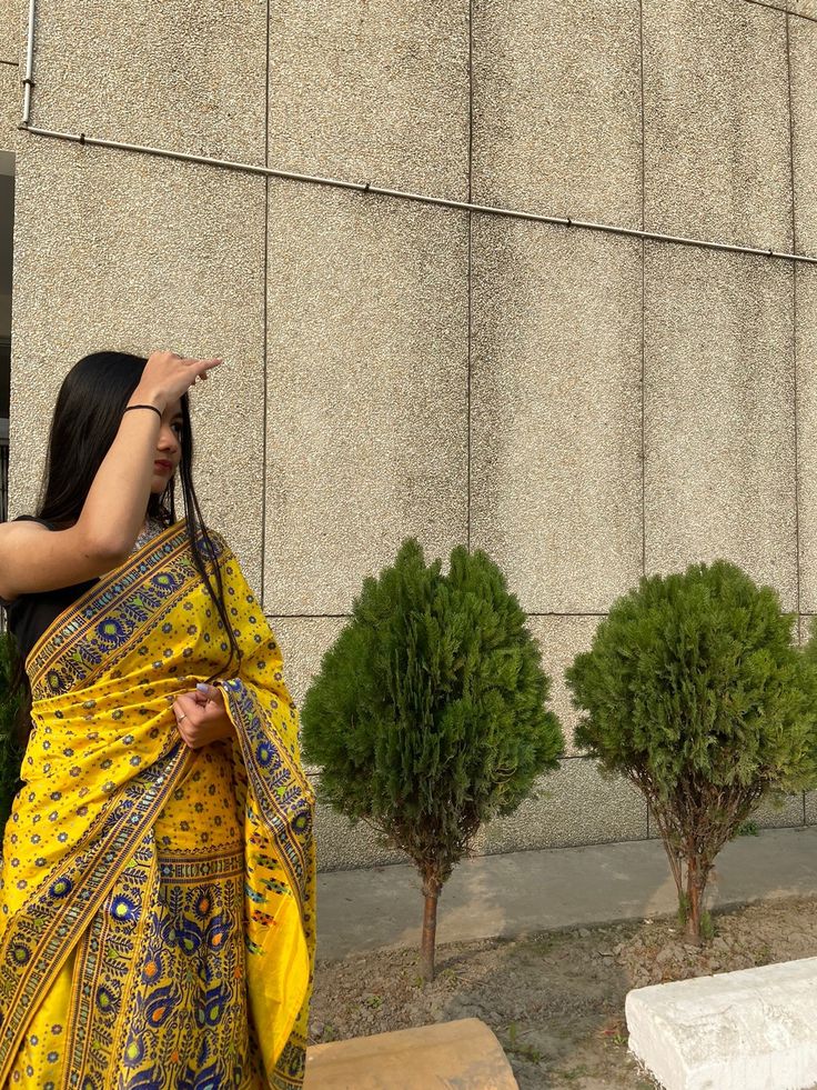 a woman in a yellow and blue sari pointing at something off to the side