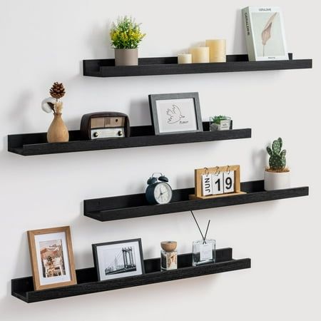 two black floating shelves with pictures and other items on them, one shelf has an alarm clock