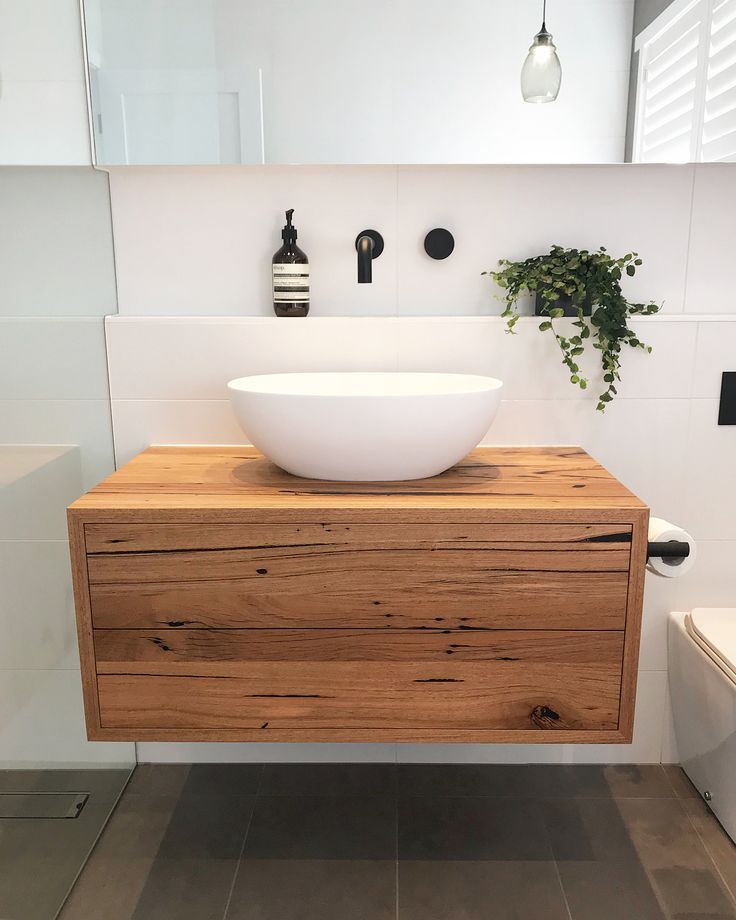 a bathroom sink with a wooden cabinet underneath it and a potted plant on the counter