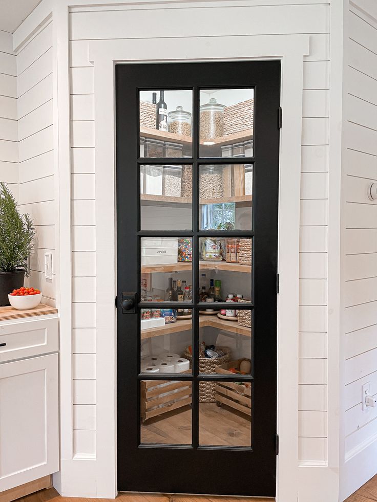 Corner pantry, pantry with black glass door, organized pantry, pantry with wood stained shelves, baskets inside pantry, space saving pantry ideas, shiplap kitchen Corner Pantry Glass Door, Industrial Pantry Door, Farmhouse Kitchen Pantry Door, Corner Pantry Design Farmhouse, Kitchen Pantry Doors Farmhouse, Black And Glass Pantry Door, Clear Glass Pantry Door, Glass Pantry Door Ideas Modern, Large Corner Pantry