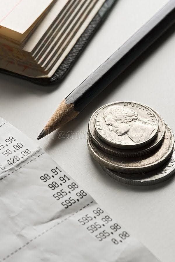 a stack of coins and a pencil on top of a paper with some receipts next to it