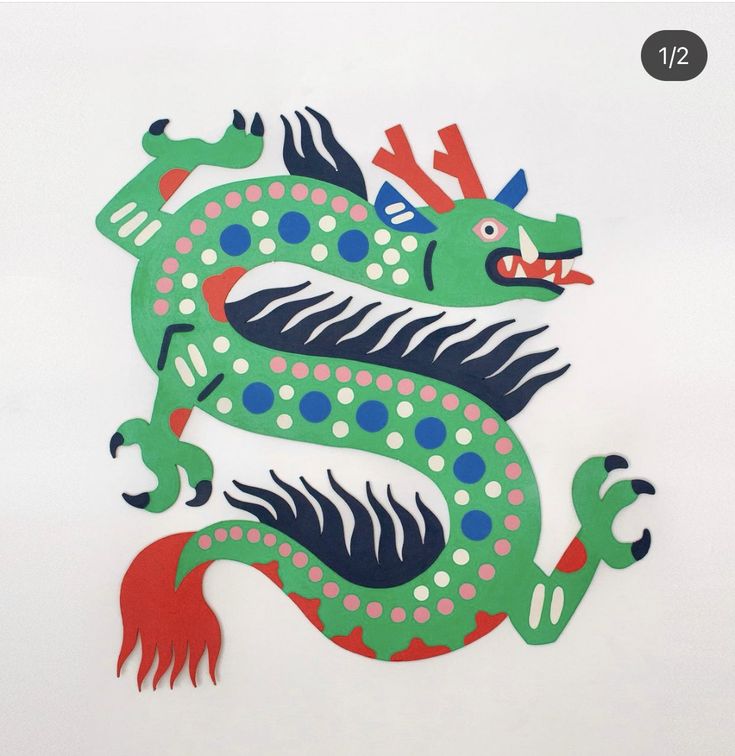 a green and red dragon sitting on top of a white wall