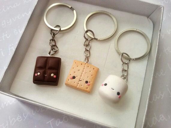 three different key chains in a box with some food on them and one is shaped like a marshmallow, the other has a piece of chocolate