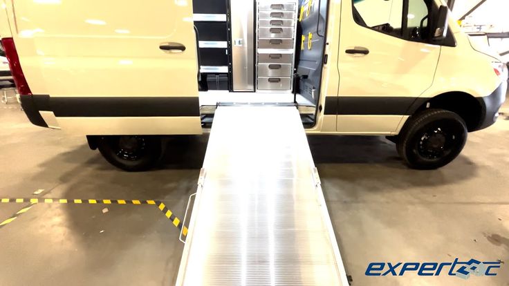 a white van parked in a garage with its door open and ramp attached to it