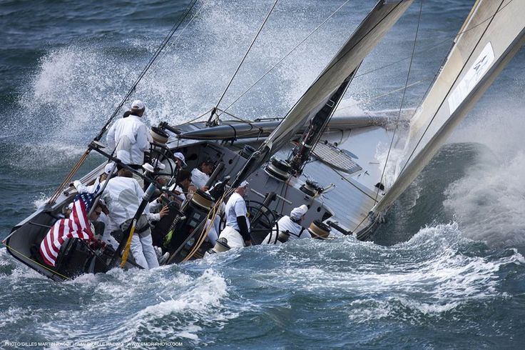 a group of people riding on the back of a sailboat in choppy water