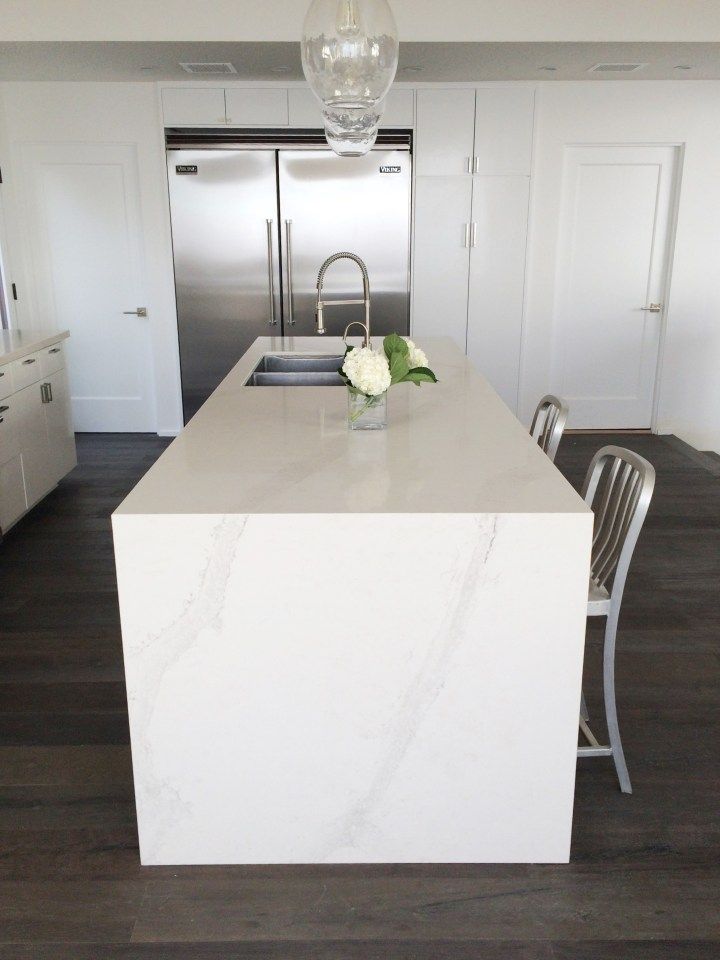 a white kitchen with an island and stainless steel appliances