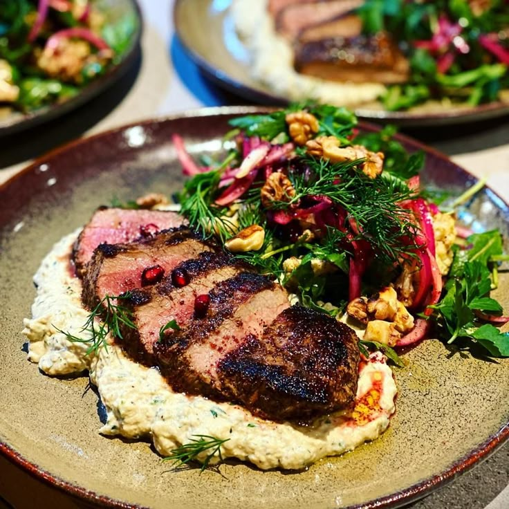 two plates with meat and vegetables on them