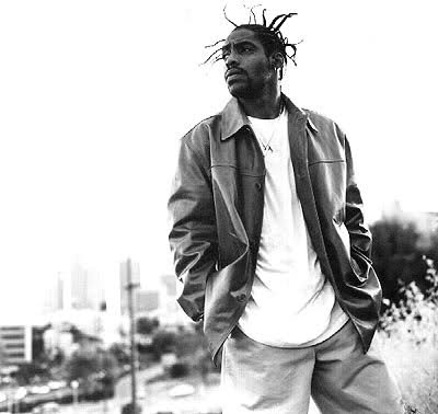 a black and white photo of a man with dreadlocks standing in the grass