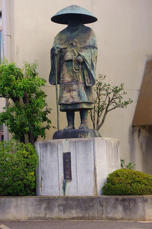 a statue of a man with a hat and cane stands in front of a building